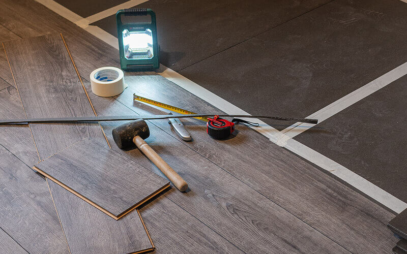 Wood flooring partially laid with tape measure and miscellaneous tools